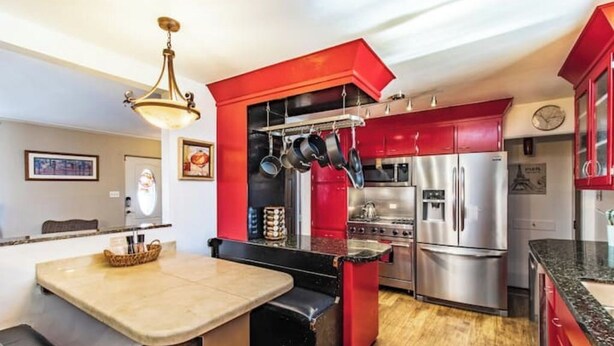 A modern kitchen with red cabinets, stainless steel appliances, and a central island.
