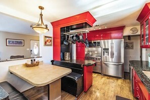 A modern kitchen with red cabinets, stainless steel appliances, and a central island.