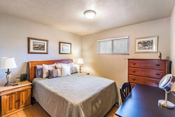 A bedroom with a bed, bedside tables, a dresser, and framed pictures on the walls.