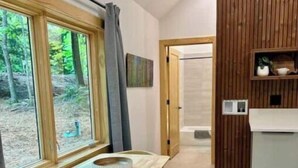 Ein Essbereich mit einem Holztisch und Stühlen, einem Fenster mit Vorhängen und Blick ins Freie.
