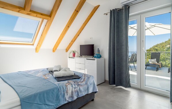 A bedroom with a bed, a TV, a desk, and a balcony with outdoor furniture. - Pet friendly home in Stanici (Stanici)