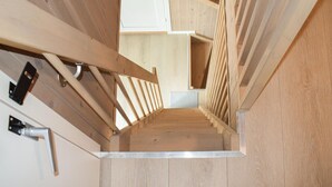 Una escalera de madera con barandilla metálica y una pared blanca con picaporte.