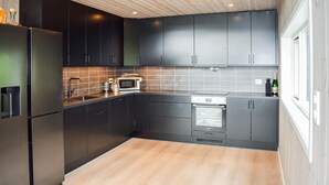 Una cocina moderna con gabinetes oscuros, electrodomésticos de acero inoxidable y piso de madera.