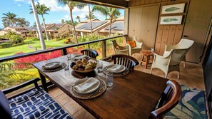Un coin repas avec une table en bois, dressée pour quatre personnes, entourée de chaises en osier.