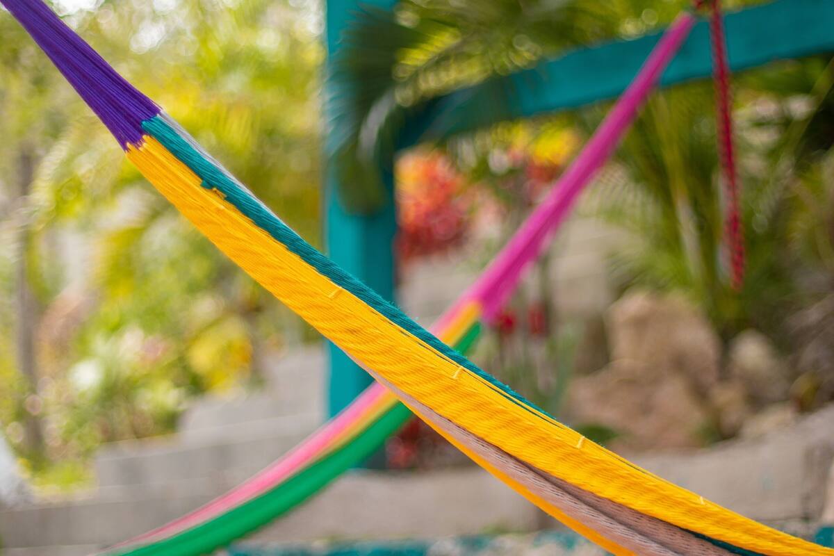 A hammock tied between a wooden structure and a stone wall.