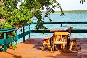 Una terraza de madera con una mesa y bancos con vista a un cuerpo de agua.