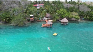 Un resort tropical con bungalows sobre el agua, aguas turquesas cristalinas y exuberante vegetación.