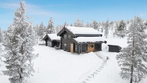 A wooden cabin complex surrounded by snow-covered trees.
