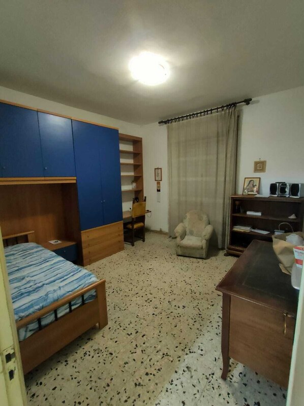 Une chambre à coucher comprenant un lit, une armoire, une chaise, un bureau et une étagère.