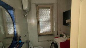 Pieni kylpyhuone, jossa on pesuallas, wc ja pesukone.