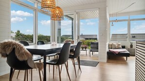 A modern dining area with a large table, chairs, and a view of the sky through large windows. - 3 bedroom nice home in Rønde (Rønde)