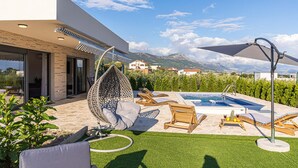 A modern outdoor pool area with a hanging chair, lounge chairs, and a small pool. - Stunning home in Kastel Novi (Kastel Novi)