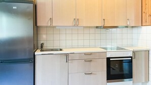 Een keuken met lichte houten kastjes, een roestvrijstalen koelkast, een spoelbak en een vaatwasser.