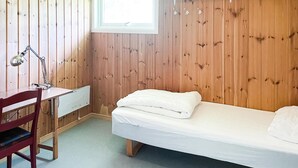Een kleine, knusse kamer met houten wanden, een enkel bed, een bureau met stoel en een raam.