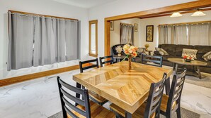 A dining area with a wooden table and chairs, a sofa, and a small table with a vase of flowers. - Walk to Eats & Events! Downtown Puyallup Home (Puyallup)
