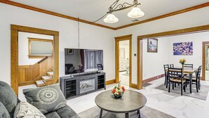 A living room with a sofa, a coffee table, a TV, and a dining area with chairs and a table. - Walk to Eats & Events! Downtown Puyallup Home (Puyallup)