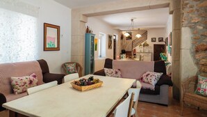 A cozy living room with a dining table, striped sofas, and a basket of pinecones. - Alojamiento rural Aloe Pozo Alcón by Ruralidays (Jaén)