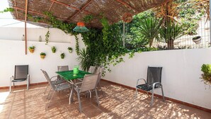 An outdoor patio with a table and chairs, surrounded by potted plants and a thatched roof. - Alojamiento rural Aloe Pozo Alcón by Ruralidays (Jaén)