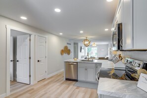A modern kitchen with white cabinetry, a dishwasher, a sink, and a built-in oven.
