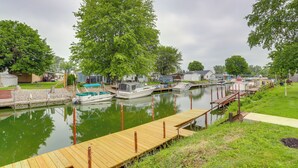 Un port de plaisance avec des bateaux amarrés, une jetée en bois et une rangée de maisons le long de la rive.