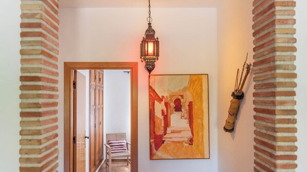 A hallway with a wooden door, a hanging lantern, and a painting on the wall. - Casa Villa Pinale Álora by Ruralidays (Málaga)