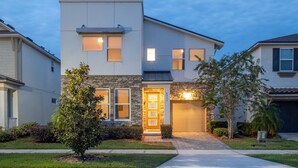 A modern two-story house with a stone facade, a front door with a display, and a garage. - Family Ready Pool Villa with Star Wars Game Room, Karaoke (Kissimmee)