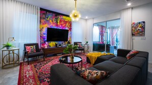 A modern living room with a large flat-screen TV, a sofa set, a coffee table, and a vibrant rug. - Family Ready Pool Villa with Star Wars Game Room, Karaoke (Kissimmee)