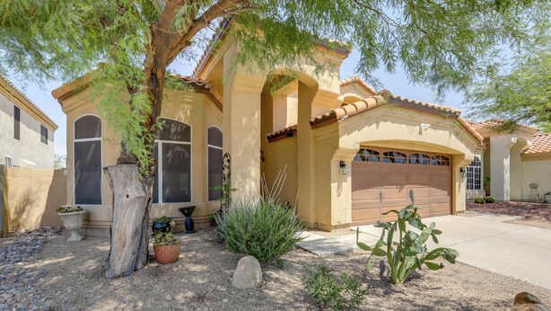 A residential house with a garage, a large tree, and various potted plants in the front yard. - Cookout Ready! Desert Oasis w/ Pool in Goodyear (Goodyear)