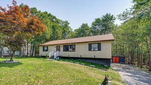 A single-story house with a front porch, a small yard, and a pathway leading to the house. - 'A Time to Remember' Home in Tobyhanna w/ hot tub (Tobyhanna)
