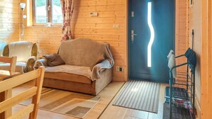 A cozy cabin interior with a sofa, chair, and a door with a unique light fixture. - 2 bedroom gorgeous home in Darlowo (Darlowo)