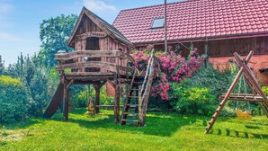A wooden structure with a red roof, a wooden staircase, and a swing set. - 2 bedroom gorgeous home in Darlowo (Darlowo)