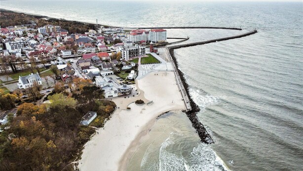 An aerial view of a coastal town with a sandy beach, a promenade, and a breakwater extending into the sea. - 2 bedroom gorgeous home in Darlowo (Darlowo)
