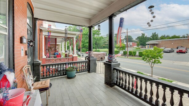 A covered porch with a brick wall, a table with a red umbrella, and a view of the street. - < 2 Mi to Downtown & Capitol: Harrisburg Hideaway (Harrisburg)