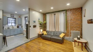 A living room with a sofa, a small table, and a kitchen area with cabinets and a refrigerator. - < 2 Mi to Downtown & Capitol: Harrisburg Hideaway (Harrisburg)