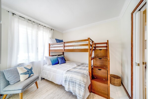 Un dormitorio con una cama alta, un sofá y una mesita de noche.