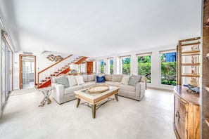 Un salon spacieux avec un grand canapé d’angle, une table basse en bois et un escalier doté de rampes en bois.
