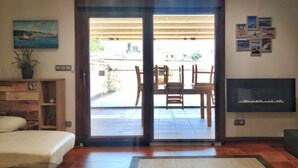 A room with a bed, a TV, a sliding door to a patio with a table and chairs, and a plant on the left. - Desconectaengalicia Townhouse Vichona 2.5 km from the center of Sanxenxo (Forxán)
