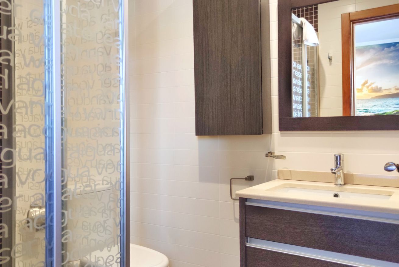 Une salle de bain équipée d’une douche, d’un lavabo, d’un miroir et d’un porte-serviettes.