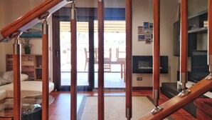 A living room with a sofa, a glass coffee table, a TV, and a staircase with wooden railings. - Desconectaengalicia Townhouse Vichona 2.5 km from the center of Sanxenxo (Forxán)