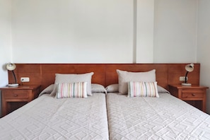Un lit double avec une tête de lit en bois, deux tables de chevet avec des lampes et des coussins à rayures.