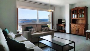 Una sala de estar con un sofá, una mesa de centro, un televisor y un aparador de madera.