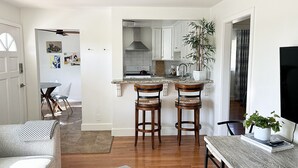 Een moderne keuken met een centraal eiland, houten stoelen en een plafondventilator.