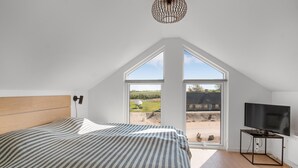 Ein Schlafzimmer mit einem großen Bett, einem Fernseher und Blick ins Freie.