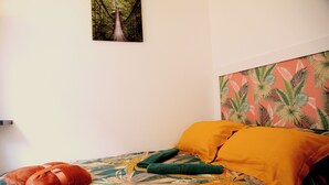A bed with a floral bedspread, a green pillow, and an orange pillow. - THE ISLE PARADISE (Saint-Quentin)