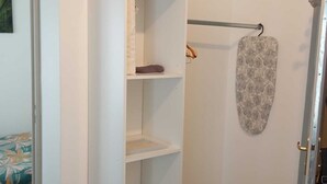 A white closet with open shelves, a hanging rod, and a patterned towel. - THE ISLE PARADISE (Saint-Quentin)