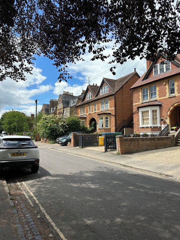 A residential street with brick houses, a parked car, and a clear sky.
