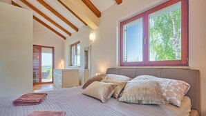 A bedroom with a large bed, a window with a view of greenery, and a balcony with a chair. - 2 bedroom lovely home in Kladje (Kladje)