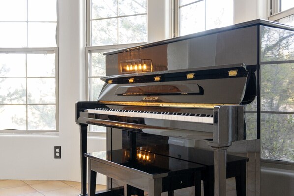 A grand piano in a room with large windows.