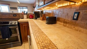 A kitchen with a tiled backsplash, stainless steel appliances, and a countertop with a grid pattern.