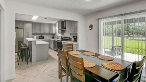 A modern kitchen with grey cabinets, a central island, and a dining area with a table and chairs. - Updated 4 bedroom home in Oragnefield (Orange)